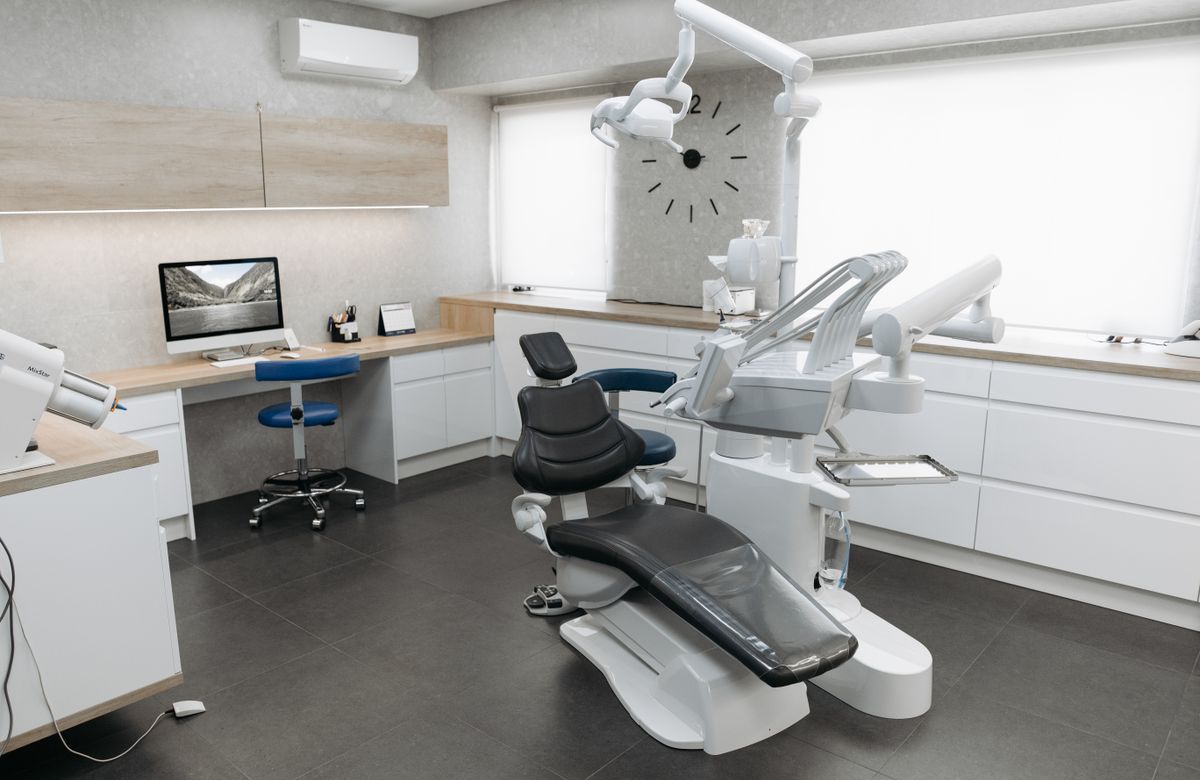 Sala de atendimento odontológico com cadeira e armários claros, em um ambiente organizado